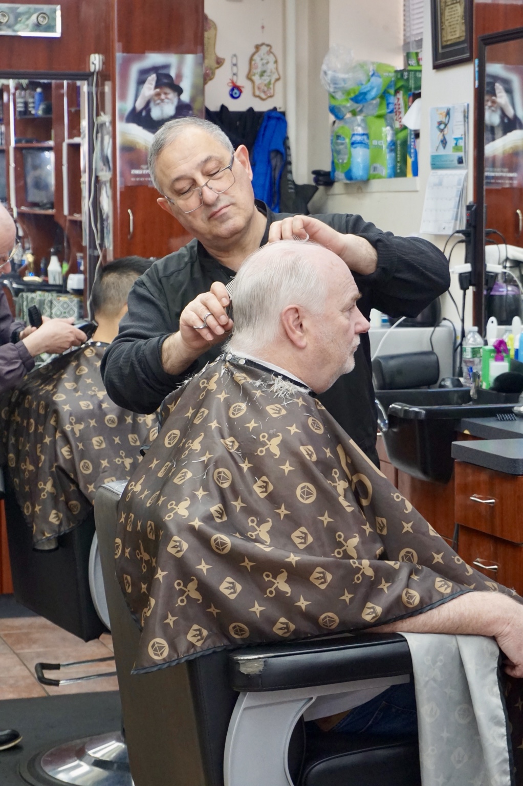 A barber working on a haircut inside the shop