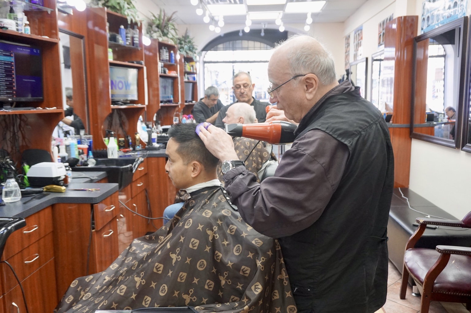 A barber trimming a customer’s hair